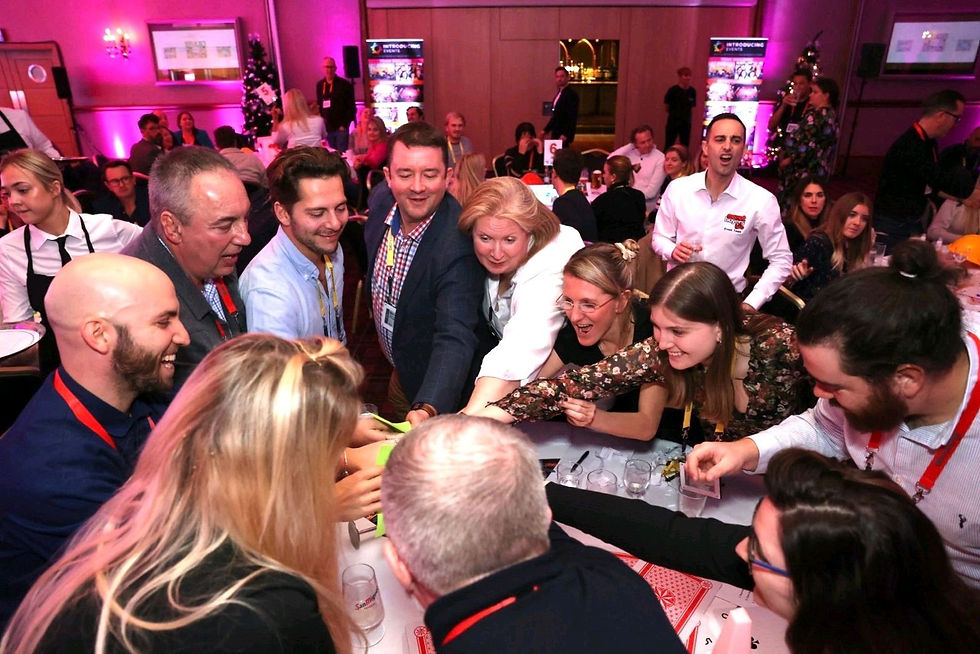 People working together having fun at a work Christmas party sharing Christmas party ideas and skills in order to become champions. The photo shows one of the games in a Christmas gameshow event for a work Christmas party idea.