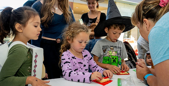 Children dressed in halloween costumes at a white table