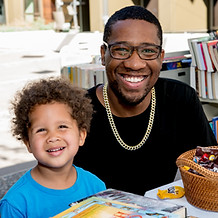 A man and his son sitting at a table in front of a stack of books