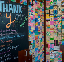 A chalkboard wall with “Thank you” written, next to it a wall full of sticky notes with different notes on them