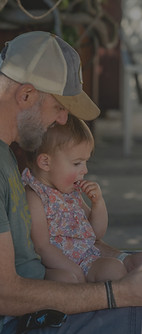 A man in a hat reading to a child on a bench