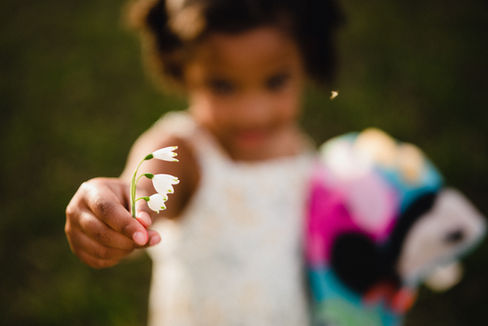 Little girl holding a white flower to the camera