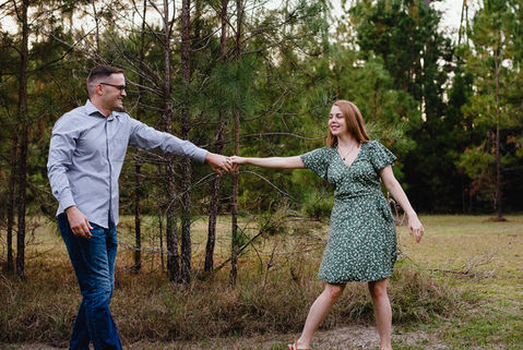 Man and woman dance near tree line