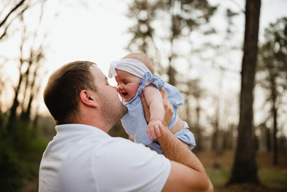 dad holds up baby girls and plays with her