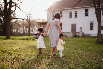 Two little girls walking away while holding moms hands