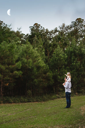Man holds child on his shoulders while looking at the moon