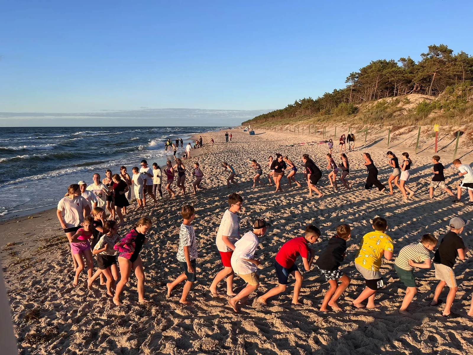 Grupa uczestników bawi się na plaży nad morzem