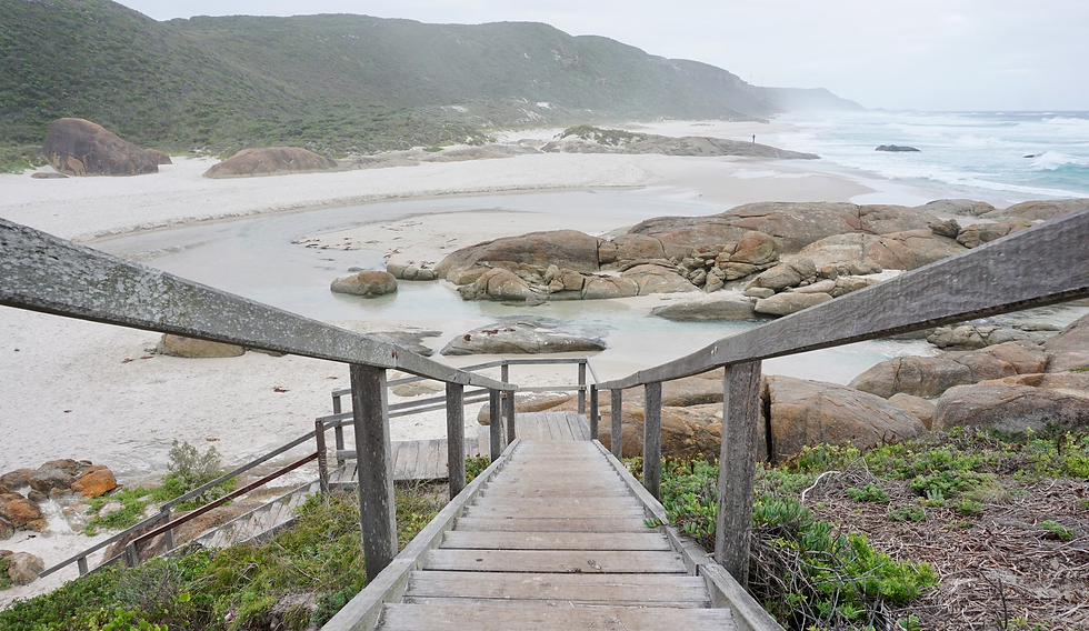 a-wooden-staircase-leading-to-a-sandy-beach
