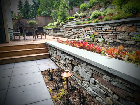 Two tiers of dry stacked raised flower beds alongside formal square walkway pavers