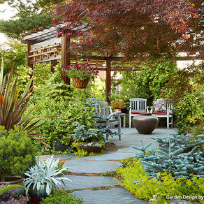 Outdoor sitting area with an open wooden gazebo and stone paver path surrounded by beautiful landscape