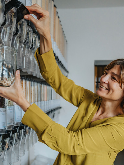 Smiling woman filling a jar from a store dispenser, showing how easy and efficient self-service is for a business.