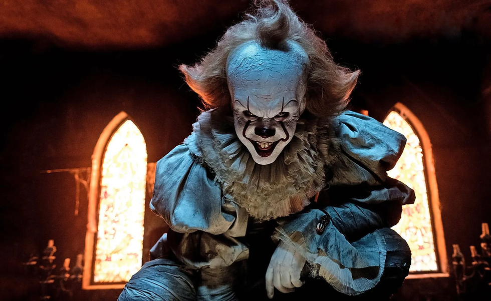 Menacing Pennywise clown crouches in a dark room, grinning with glowing windows behind him.