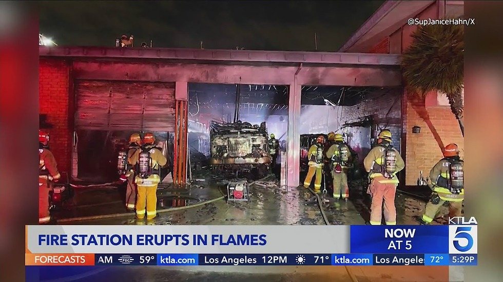 Firefighters inspect a burned fire station garage at night as KTLA 5 reports FIRE STATION ERUPTS IN FLAMES. LA County Fire Station 164 in Huntington Park