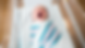 Newborn baby yawning, wrapped in a white and striped blanket. The baby lies in a hospital bassinet with a peaceful, sleepy expression.
