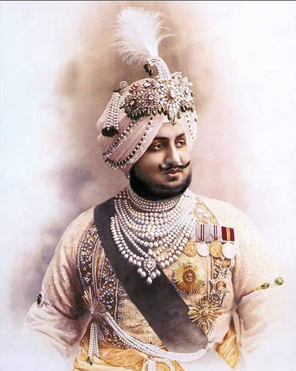 Ornate portrait of an Indian prince in a jeweled turban and pearl necklaces, wearing medals against a soft pastel backdrop.