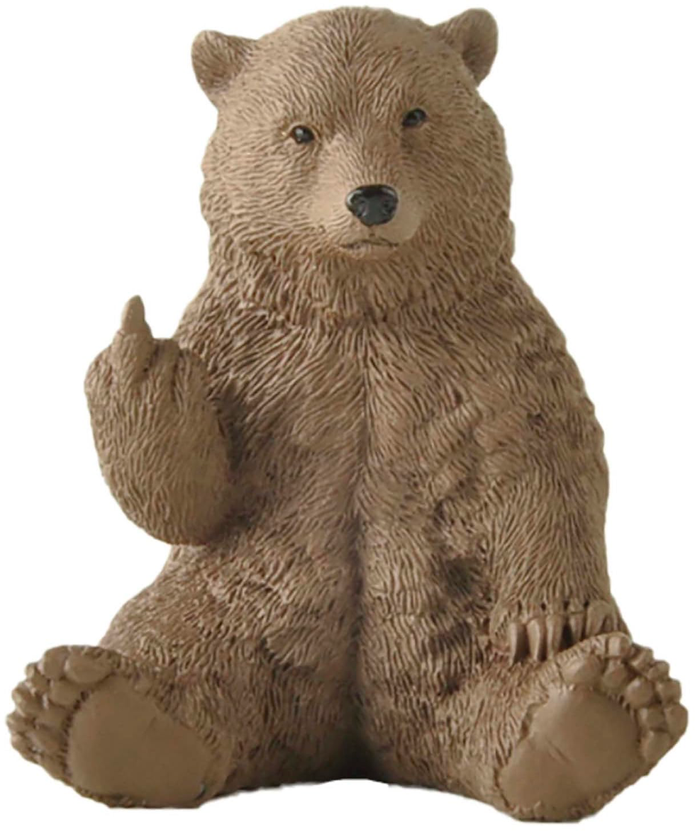 A brown bear figurine sitting with its left paw raised, resembling a hand gesture. The bear has a neutral expression against a plain background.