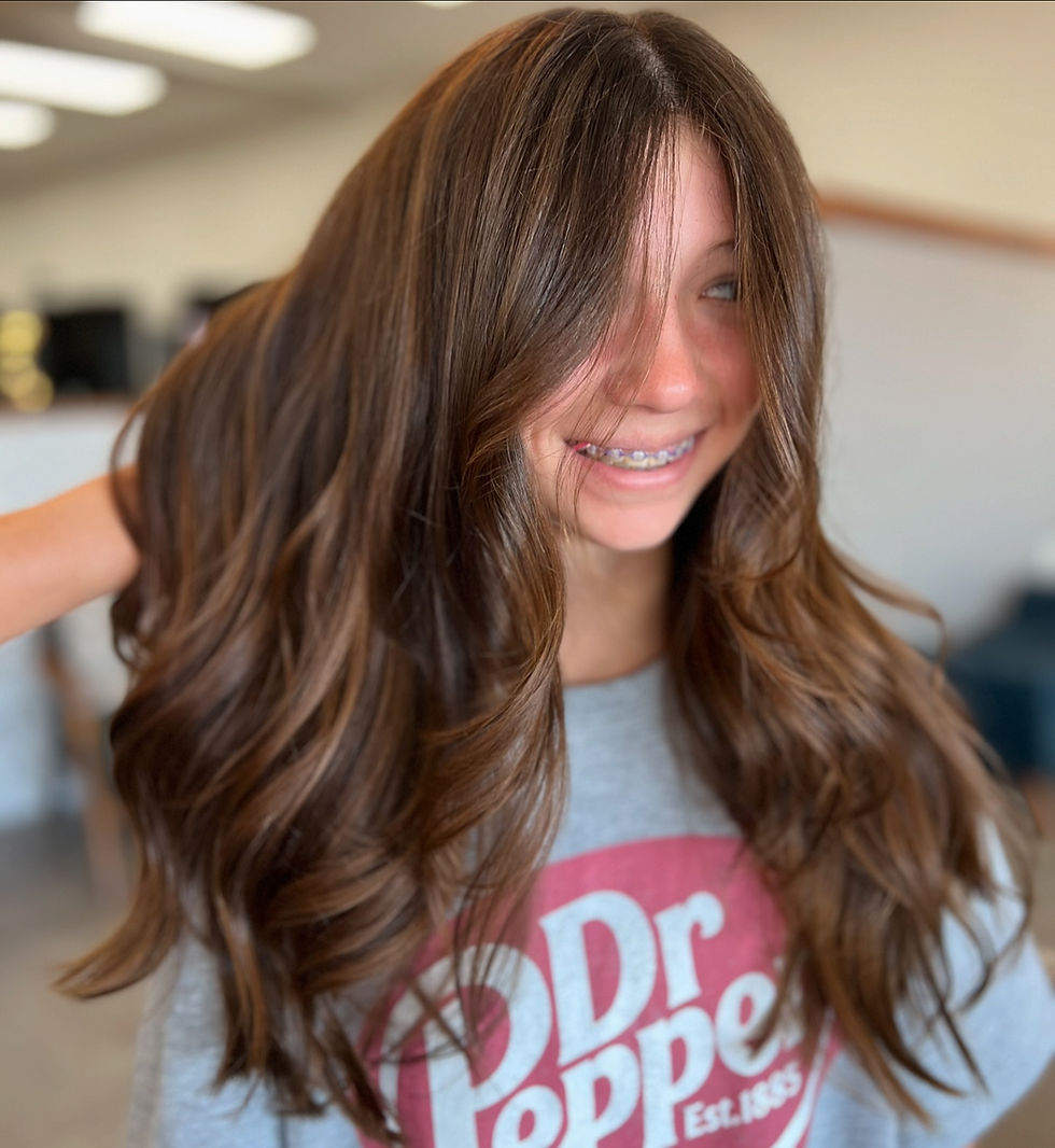 Smiling girl with long, wavy brown hair wearing braces.
