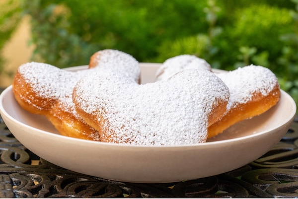 Mickey Head Shaped Beignets on a plate covered in powdered sugar