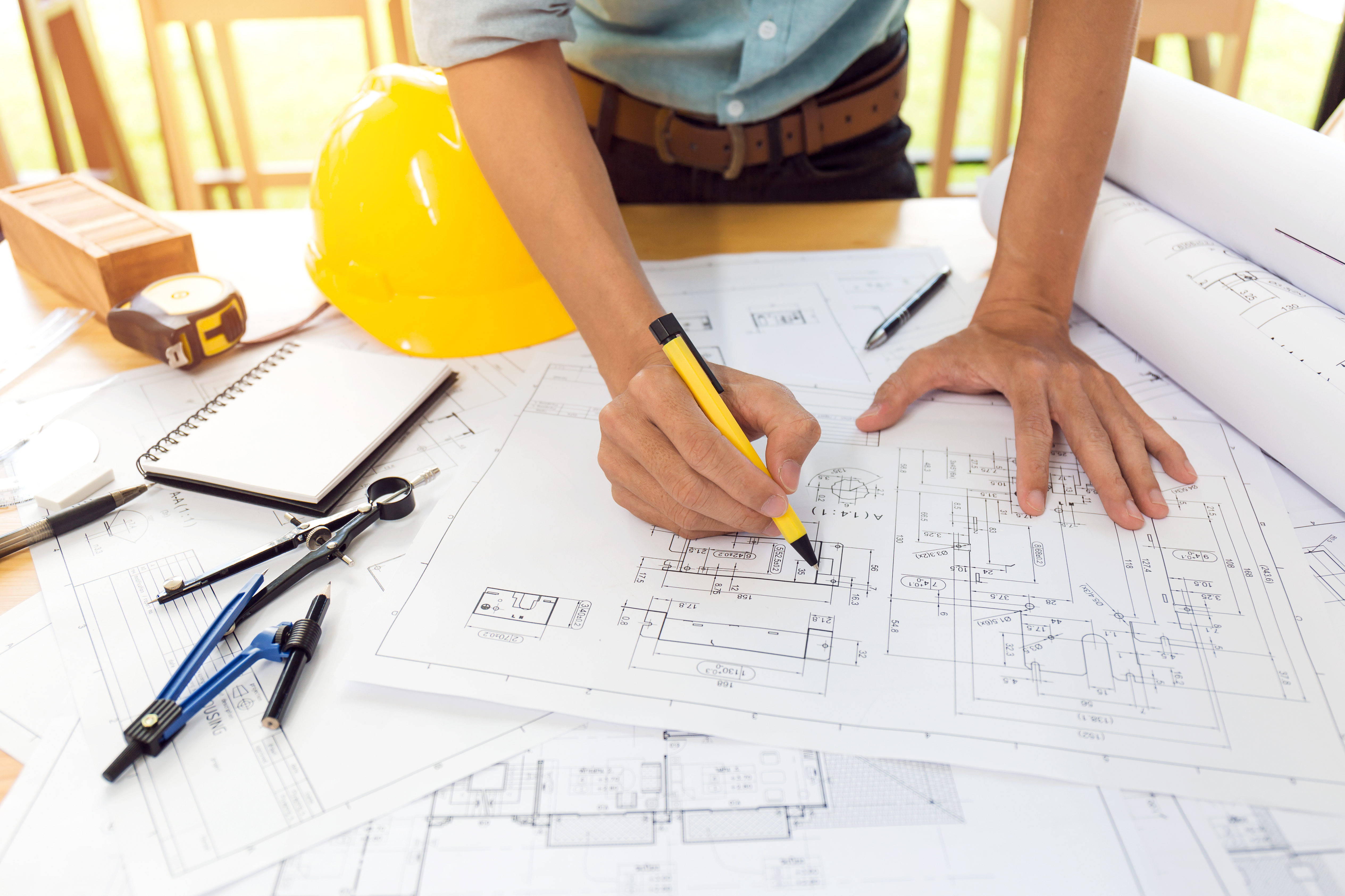 Construction engineer in Florida analyzing design trends on a blueprint for a commercial renovation project.