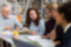 Adult learners discussing coursework together in a collaborative study session at a library.