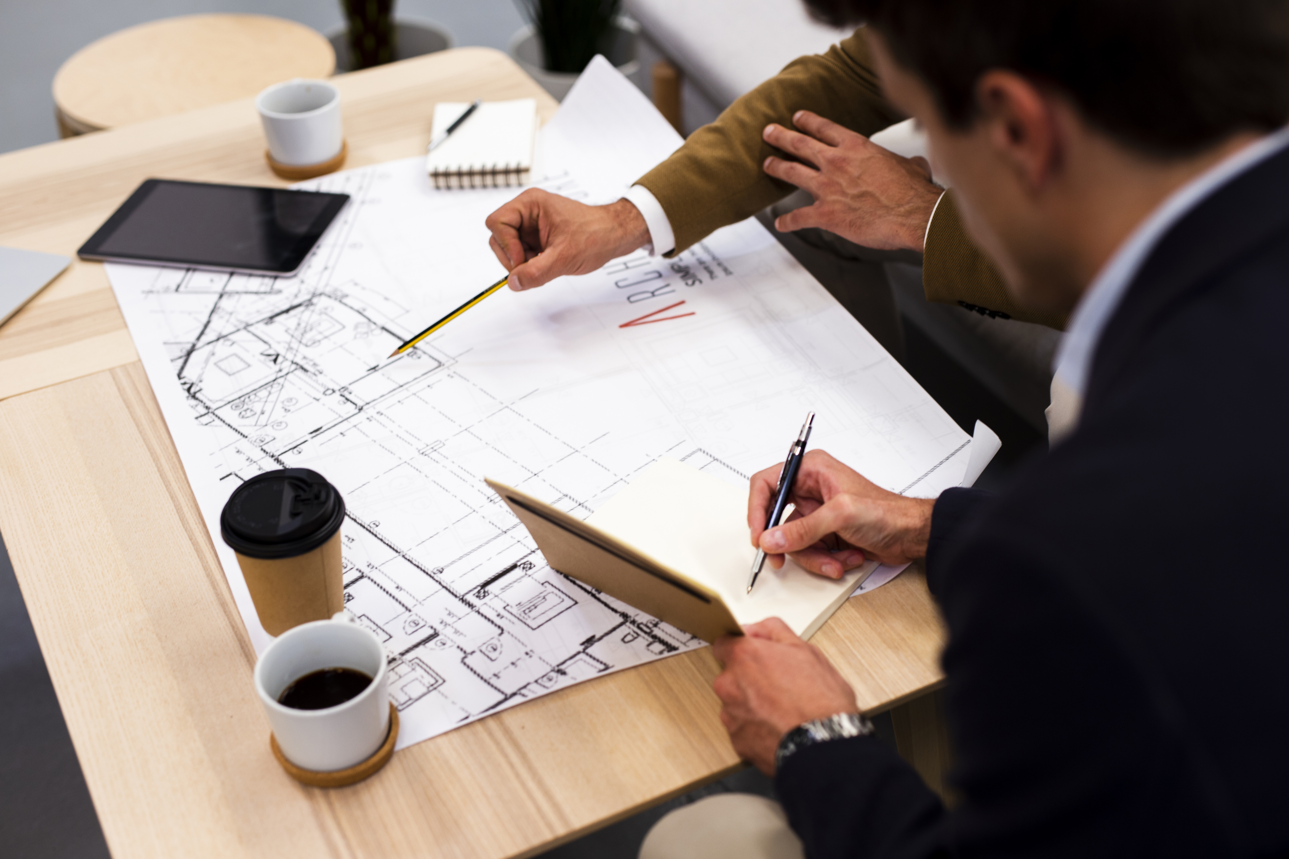 An architect reviewing blueprints and financial documents on a desk, symbolizing the planning and budgeting process in commercial renovations.