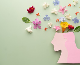 Mental Health Awareness Month. Woman head with colorful fresh flower on green background.