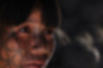 A woman looks at the camera, has traditional facial tattoos