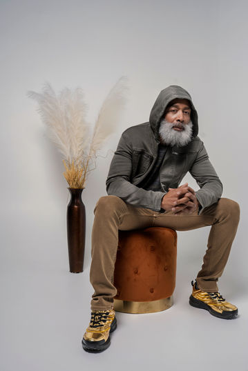 a man in a hooded jacket sits on an orange ottoman