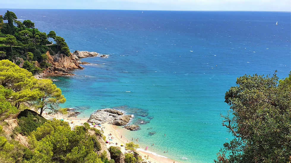 Small Cala Boadella cove with golden sand and rocky surroundings, perfect for a peaceful day.