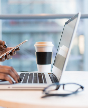 Consultation Image, individual holding a phone with a laptop open.