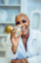 Samira holding a House of Iyrah Nocturne perfume bottle and smiling.