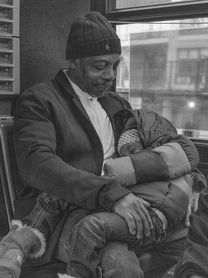 Candid black and white photograph of a man lovingly holding and looking down at a sleeping child