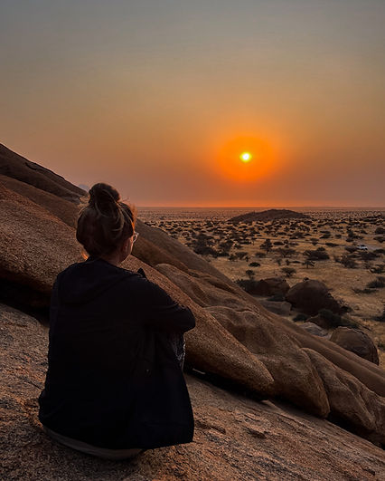 Eine Frau bei einem traumhaften Sonnenuntergang an der Spitzkoppe in Namibia auf einer Selbstfahrerreise