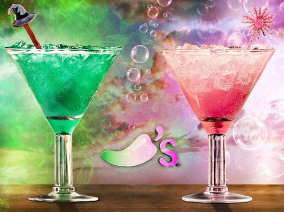 Two colorful cocktails on a table; one green with a witch hat stirrer and one pink with a star stirrer. Chili's logo in between.