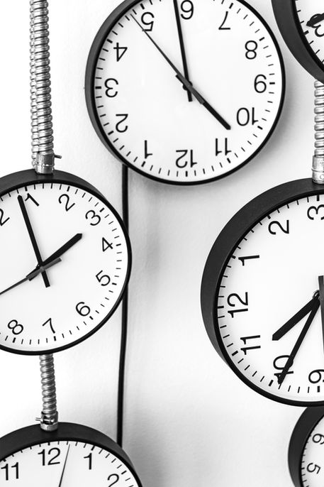 Several round clocks with white faces mounted on wall, connected by flexible metallic conduits – Photography from the series 'Transgression durch Hoffnung' by Alfred Stoll, 2025–2026. Metamodern Art; Exhibition kultur.lokal.fürth; Metamodernism; Metamodern Grotesk.