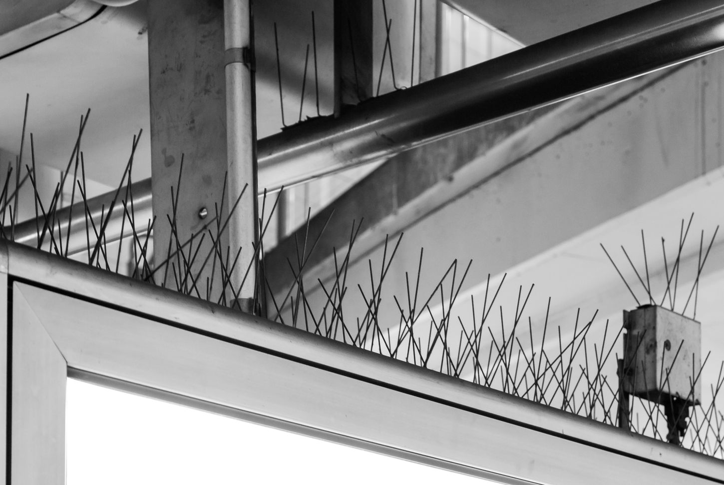 Close-up of anti-bird spikes on architectural beams, geometric composition with chaotic pattern of thin metal rods – Photography from the series 'Transgression durch Hoffnung' by Alfred Stoll, 2025–2026. Metamodern Art; Exhibition kultur.lokal.fürth; Metamodernism; Metamodern Grotesk.