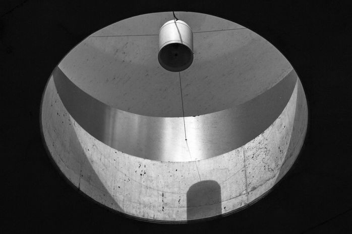 Kreisförmige Öffnung in Betonstruktur, zylindrische Lichtquelle hängt in der Mitte – Fotografie aus der Serie 'Transgression durch Hoffnung' von Alfred Stoll, 2025–2026. Metamodern Art; Ausstellung kultur.lokal.fürth; Metamodernism; Metamodern Grotesk.