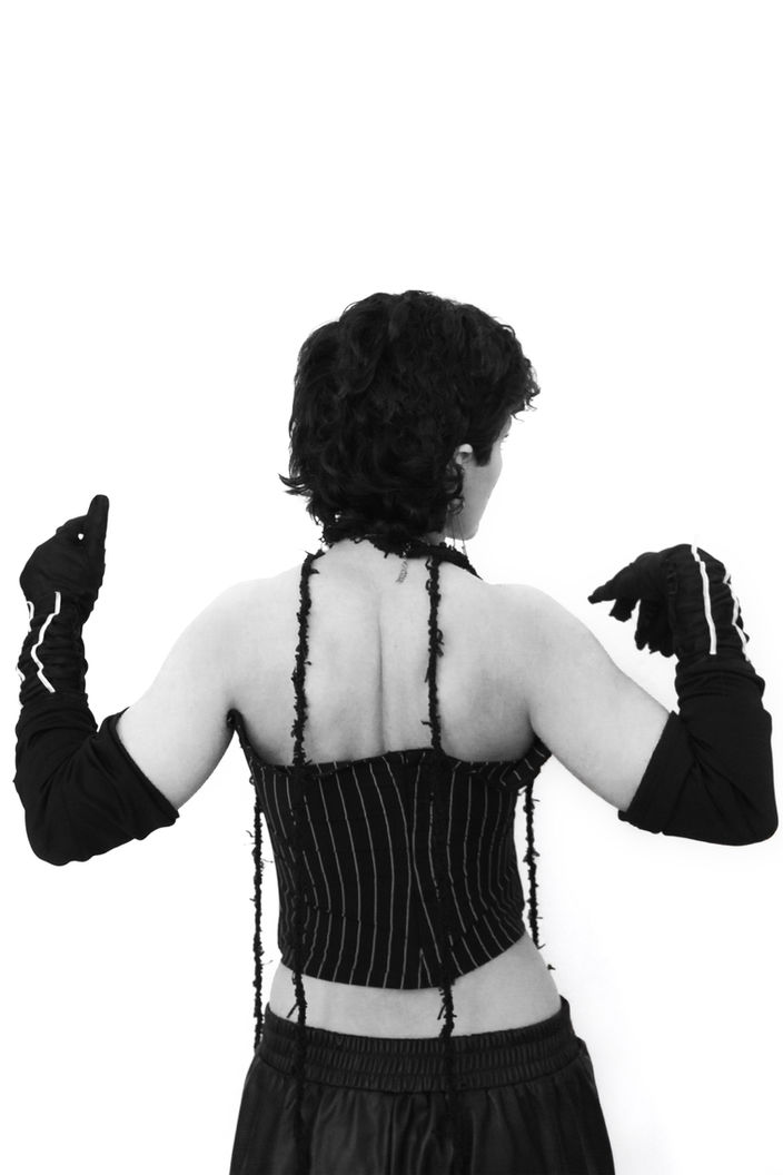 Rückenansicht einer Person in Korsett und Handschuhen, zwischen Verletzlichkeit und Stärke – Fotografie aus der Serie 'Transgression durch Hoffnung' von Alfred Stoll, 2025–2026. Metamodern Art, Metamoder Grotesk