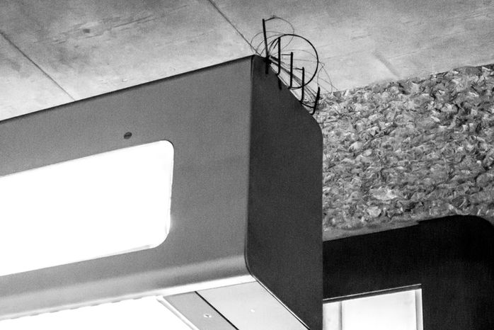 Corner of a dark rectangular object with bird spikes and tangled wire on top edge – Photography from the series 'Transgression durch Hoffnung' by Alfred Stoll, 2025–2026. Metamodern Art; Exhibition kultur.lokal.fürth; Metamodernism; Metamodern Grotesk.