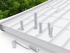 Metal screws and bolts stand on a white grooved surface with a leafy green background, creating a clean and organized look.