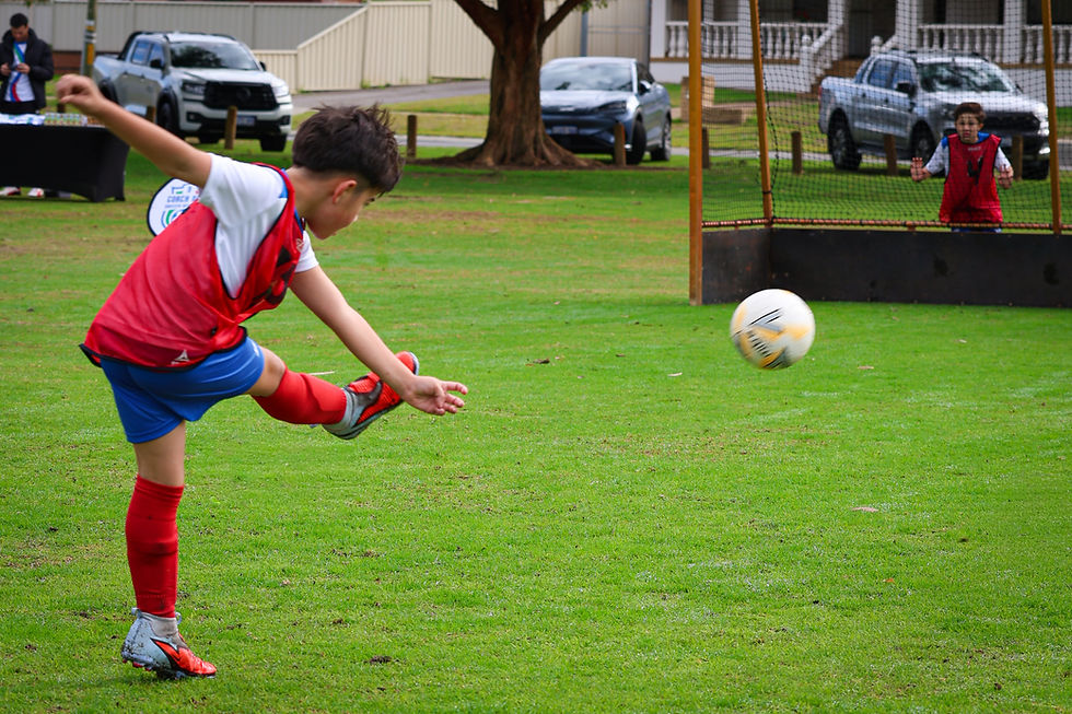 A young player practicing solo soccer rebound passing drills against a brick wall in a grassy Perth backyard