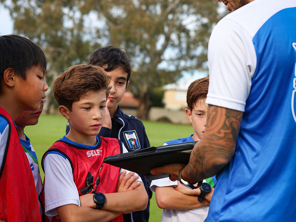 A professional youth soccer coach guiding a young player constructively during a training session