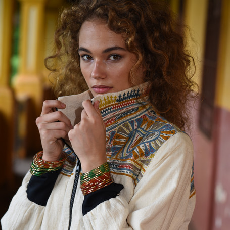 Woman wearing a white jacket with colorful hand-embroideries in organic cotton