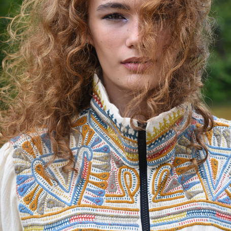 Woman wearing a white jacket with colorful hand-embroideries in organic cotton