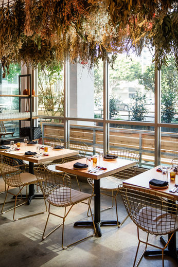 view at tables overlooking outside the restaurant with botanical piece above showcasing design