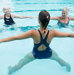laechelnder-weiblicher-trainer-mit-aelteren-frauen-die-im-schwimmbad-trainieren_107420-974