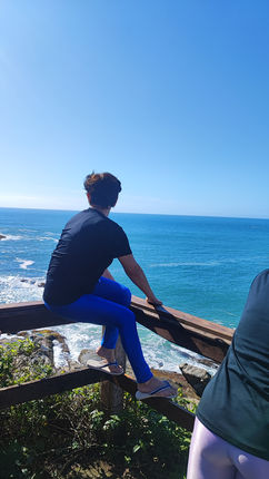 Participante sentado em mirante contemplando o mar 