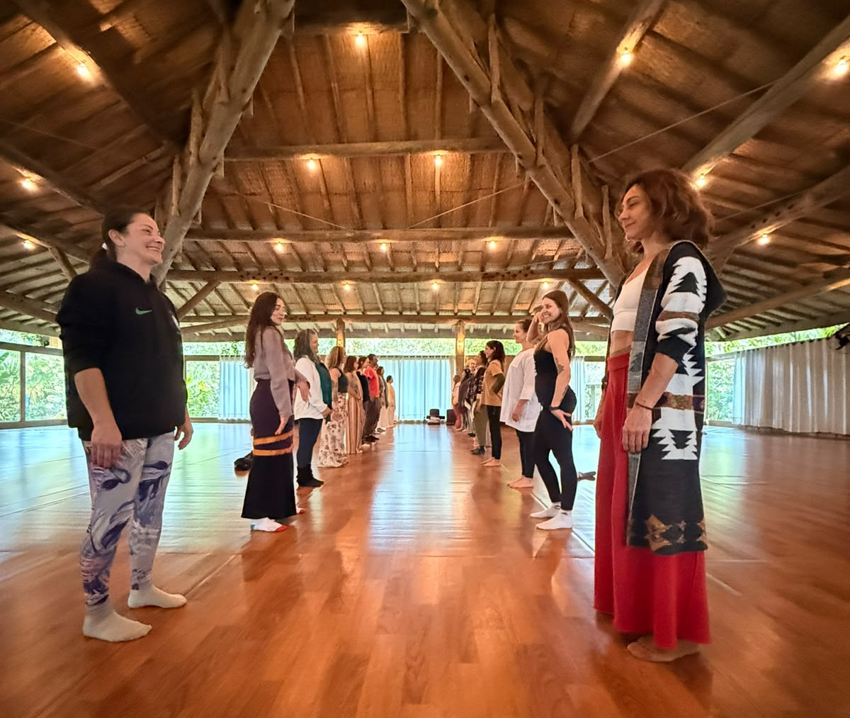 Duas filas de pessoas em pé, de frente uma à outra em meditação ativa em amplo templo