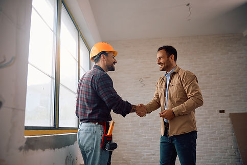 Happy manual worker greeting his client at construction site. Copy space..jpg