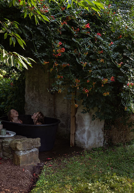 Two girls enjoying outdoor tub, old stone, flowers